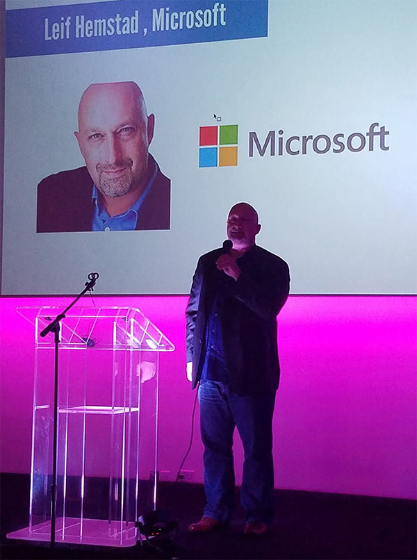 Leif Hemstad speaking on stage Microsoft affiliation and logo in background